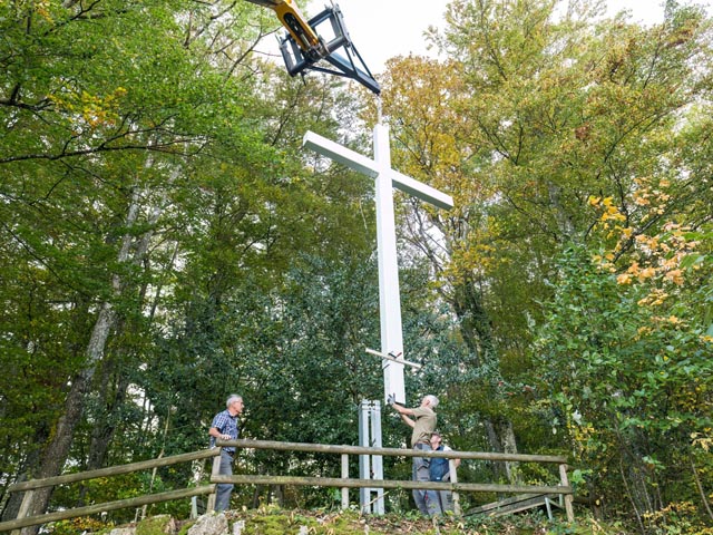 Mit Hilfe des Teleskopladers wird das neue Kreuz in die Verankerung eingefügt. Foto. Edwin Rüede