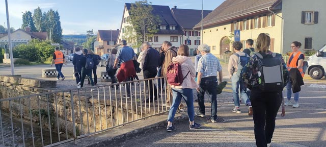 Die Teilnehmenden folgen der Pedibusroute und diskutieren weitere Gefahren des Schulwegs, etwa das fehlende Geländer am Bach. Foto: VCS Aargau / zVg