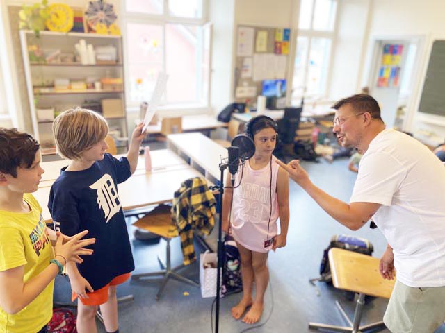 Macher Peter Geiselhart, Jugendarbeiter beim schjkk, mit einer Schülerin und zwei Schülern der 3. Primarschulklasse in Rheinfelden beim Üben für die grosse Bühne. Foto: Sonja Fasler
